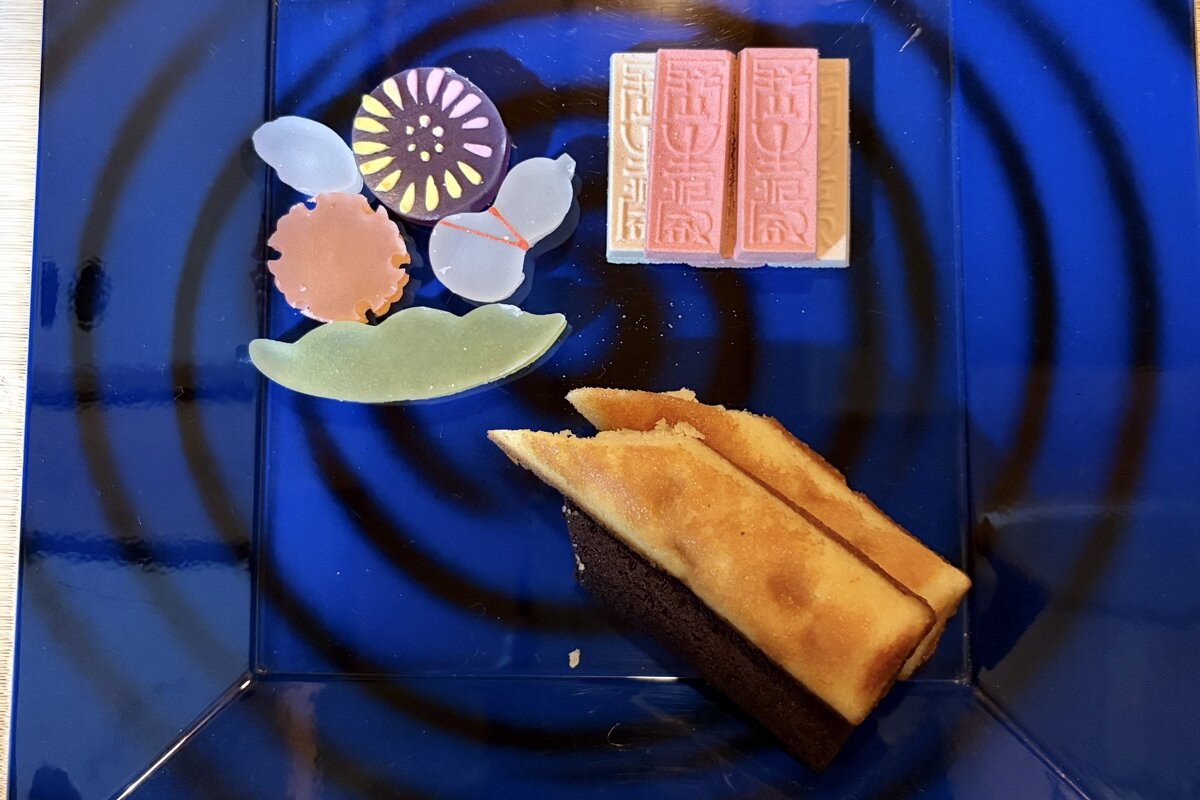 青い渦模様の菓子器に、菊や瓢箪の形のかいちん、紅白の長生殿、お土産のりんごのカステラが盛られている